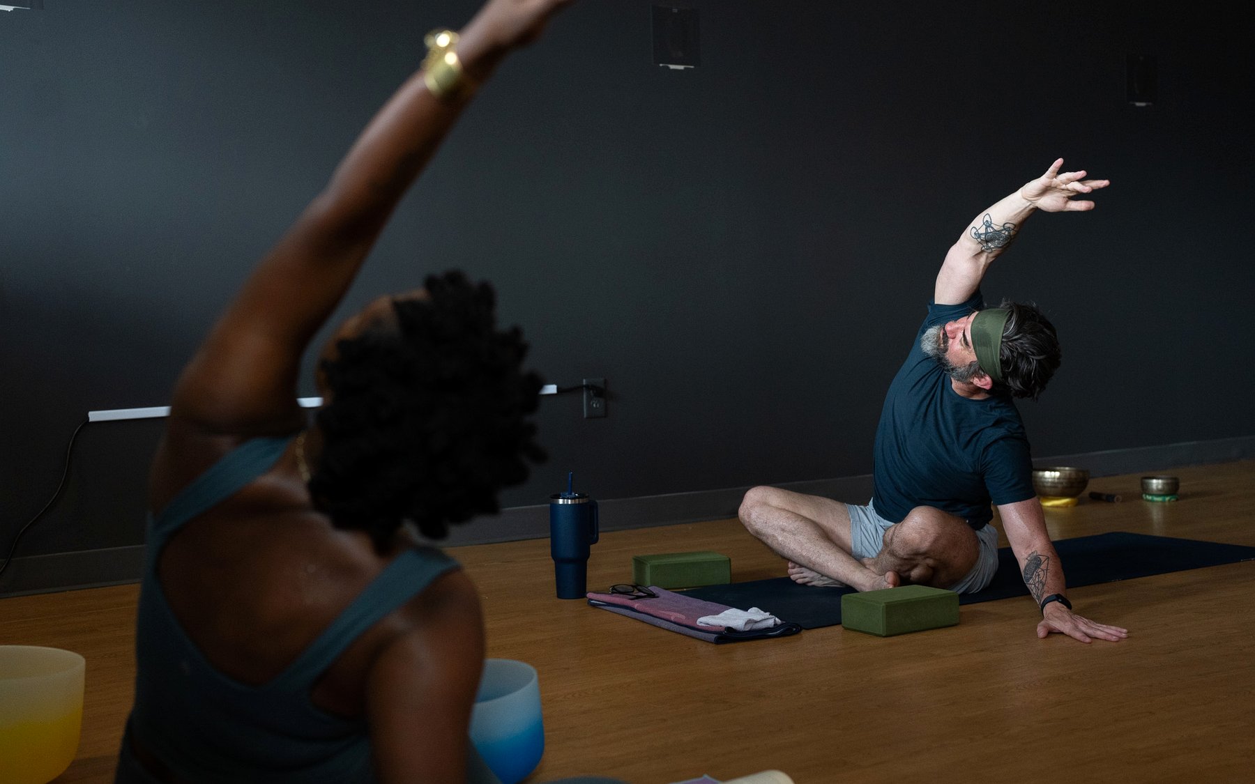 A student in a seated side stretch as a teacher guides nearby